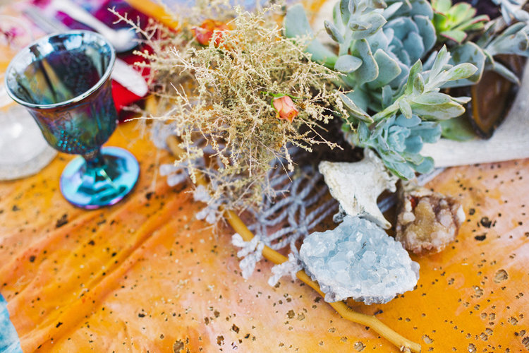 Wedding centerpiece on a table with succulents, rocks, crystals, and Mojave Macrame table runner