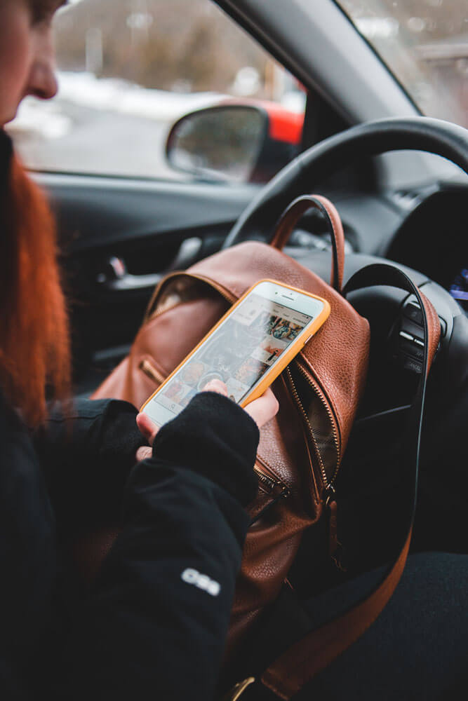 A person in the drivers seat of a vehicle checking their phone