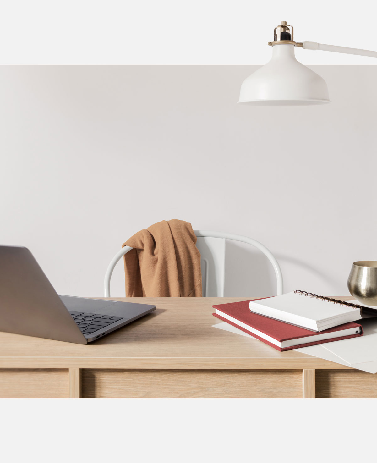 A desk with a laptop and a lamp hanging over it